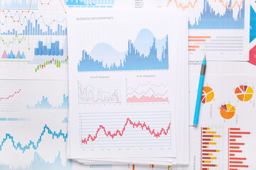 Many business graphics and diagrams with pen as background, closeup