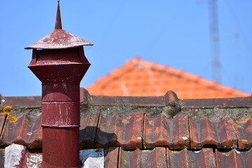 Roof top with terracotta tiles and old bent sheet metal chimney. Location: Portugal