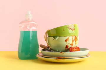 Dirty dishes with detergent on color background
