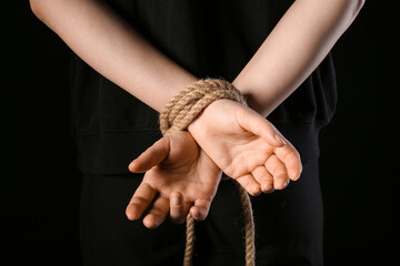 Hands tied together with rope on black background. Concept of oppression