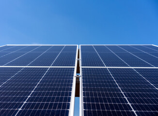 Low angle view of modern industrial solar panel against clean blue sky background