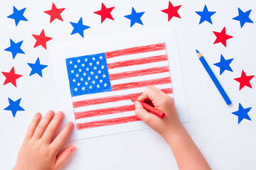 Child drawing american flag for fourth of july celebration or school project for American Independence Day. Nearby lies a blue pencil and blue and red stars