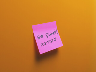 Sticky note instructing silence on a vibrant background