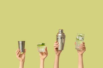 Female hands with glasses of mojito, shaker and measure cup on green background
