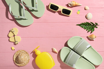 Frame made of stylish flip-flops, sunglasses and seashells on pink wooden background