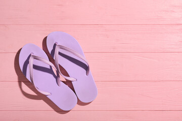 Stylish flip-flops on pink wooden background