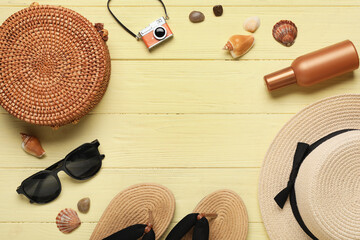 Frame made of stylish flip-flops, sunglasses, hat, bag and seashells on beige wooden background