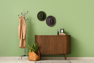 Interior of hallway with stylish hats, coat rack and commode