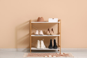 Shelf unit with felt hat and shoes near beige wall