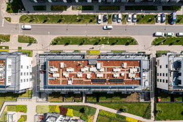 Aerial top-down view of modern apartment building with green rooftop terrace and solar panels for...