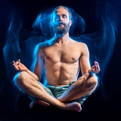 Bearded man levitating in lotus pose with glowing blue energy during meditation. Concept of inner power, spiritual awakening, and advanced yoga practice