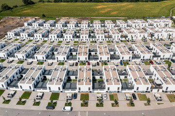 Top-down aerial view of suburban housing grid with identical two-story white homes and lawns