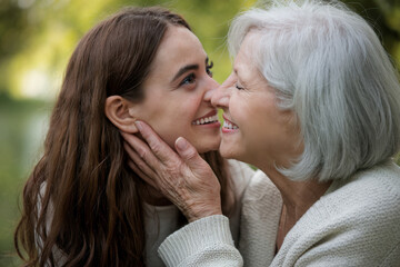Elderly Woman Holding Her Granddaughter’s Face While Smiling with Joy Outdoors