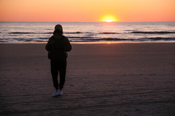 Stunning sunset in Denmark with a silhouetted figure walking along the tranquil beach