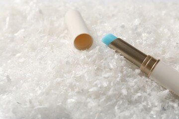 Moisturizing lip balm on artificial snow, closeup. Space for text