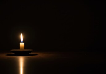 Solemn single candle lit in complete darkness with a warm reflection, symbolizing hope, remembrance, faith, and meditation.
