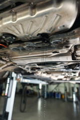 Dirty old motor oil dripping from car engine in workshop, closeup
