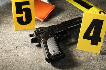 Forensic expert. Yellow crime scene tape, gun and passport on grey table, closeup