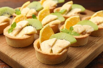 Tartlets with fruits and mint on table, closeup. Delicious dessert