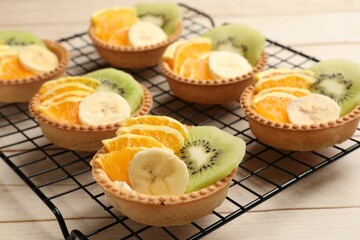 Tartlets with fruits on wooden table, closeup. Delicious dessert