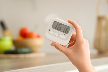 Female hand with kitchen timer in room, closeup