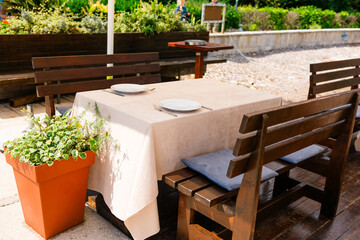 Outdoor restaurant table set for two. Summer dining, natural ambiance, and casual elegance in a sunny garden setting.