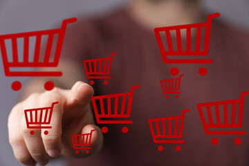 Person interacts with digital shopping carts, signifying online purchasing and e-commerce.