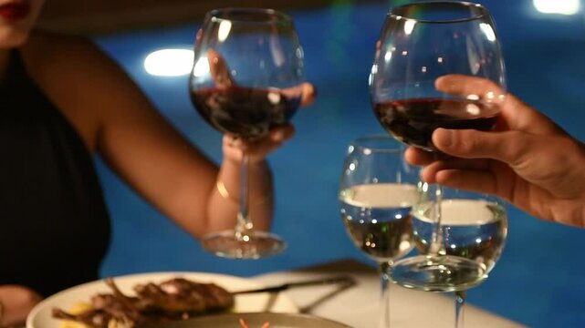 Couple clinking wine glasses during intimate poolside dinner at luxury hotel restaurant in slow motion close up - Powered by Adobe