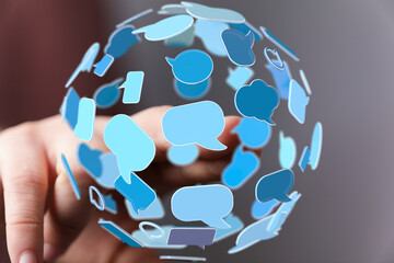 Abstract image of a hand interacting with a sphere of speech bubbles, representing global...