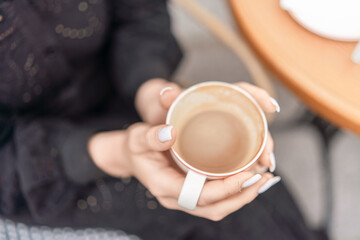 Coffee Cup Hands Relaxation: Lady holds latte outside cafe table in daytime for relaxation, drink, break.