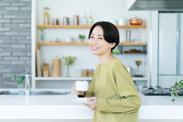 キッチンでコーヒーを飲むミドルの女性