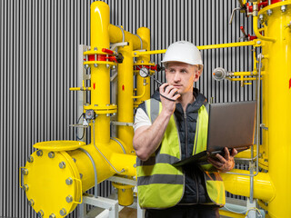 Man engineer. Technologist guy. Yellow pipes behind production foreman. Man industrialist uses...