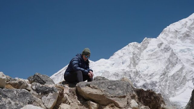 Adventurous woman pauses during high-altitude trek, surrounded by dramatic mountain landscape and winter light
