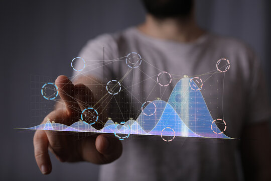 A person interacts with a futuristic holographic graph, visualizing data analysis and digital technology.