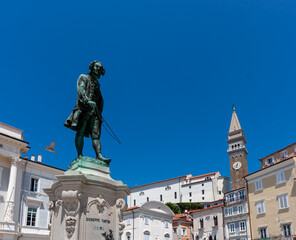 Fototapeta premium A vibrant, low-angle shot captures the iconic bronze statue of Giuseppe Tartini, the famous composer and violinist, standing prominently in Tartini Square, Piran, Slovenia