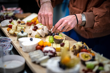 Hands Arranging a French Cheeses and Fruit Platter. assortment of french cheeses