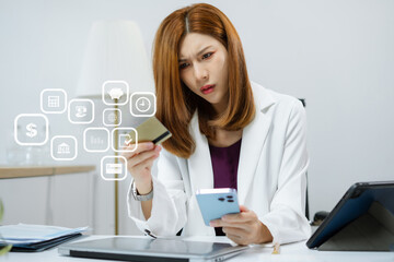 Asian woman stressed over credit card debt, holding bills in frustration. Financial anxiety and...