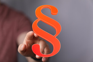 Abstract image of a hand holding a 3D paragraph symbol, representing law, legal, contract, and justice.