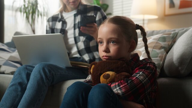 Caucasian family upset lonely kid girl suffering busy mother woman using laptop working from home ignoring child daughter holding Teddy Bear parenting ignore lack of attention childcare trouble stress