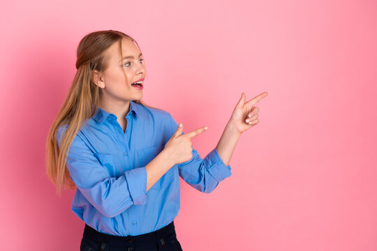 Excited schoolgirl poses against pink background, gesturing and smiling while wearing a casual outfit, promoting youthful enthusiasm