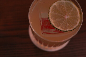 the glass of beverage with ice cube and lime slice close-up