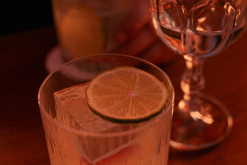 drink in glass with ice cube and lime slice near the wine glass
