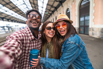 Happy tourists taking selfie at train station before departure