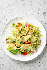 Fresh tuna salad with cucumber ribbons, red bell pepper, lettuce, and creamy dressing served on a white plate, top view, healthy homemade meal
