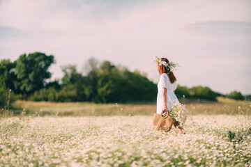 Daisy Wreath Woman: Girl walks through daisy field holding daisies in a woven bag at daytime for summer.