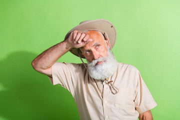 Photo of senior old man touch face hand sweating after long walk hiking wear safari suit isolated...