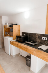 Cozy Kitchenette with Wooden Countertop, Microwave, and Black Tile Backsplash in a Warm Neutral Interior Setting