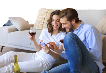 Happy couple sitting, relaxing on floor in living room, drinking red wine. Smiling young husband and wife rest at home enjoy romantic date on family weekend together on a transparent background