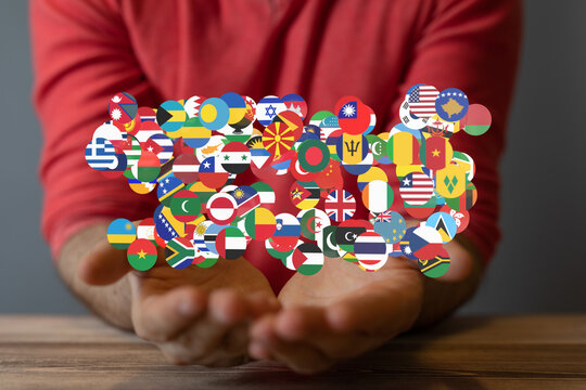 Image of hands gently cradling a collection of diverse national flags, symbolizing global unity and international cooperation.