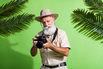 Photo of upset photographer senior man look digital camera photographing wear safari suit isolated...